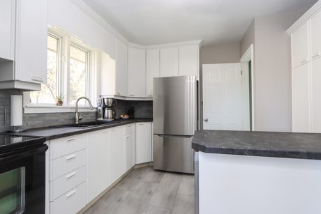 Kitchen with white cabinetry, stainless fridge and a peninsula