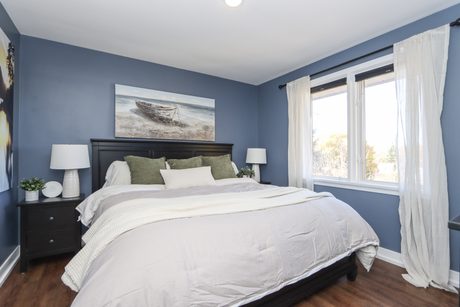Main-floor bedroom with blue walls and two windows