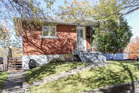 Red-brick front exterior set above the street behind mature trees